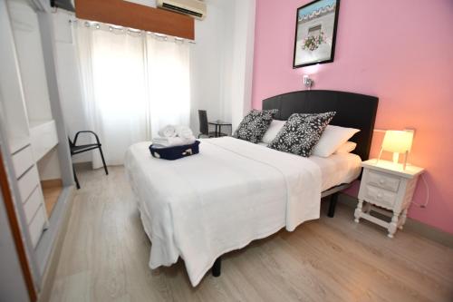 a bedroom with a large white bed and a pink wall at HB Torrevieja in Torrevieja