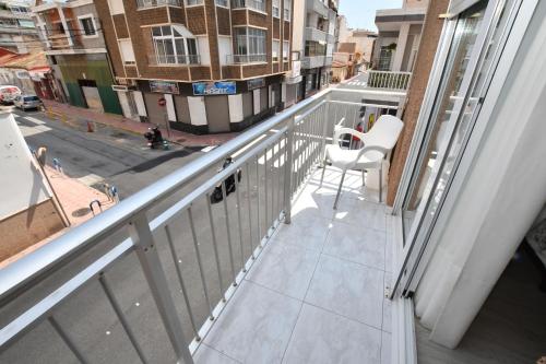a balcony with a white chair and a view of a street at HB Torrevieja in Torrevieja