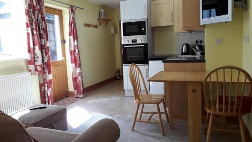 uma cozinha com uma mesa e duas cadeiras num quarto em Courtbrook Farm em Exeter