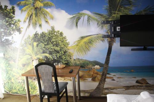 a table and chair in front of a mural of a beach at Pensjonacik ELMI in Giżycko