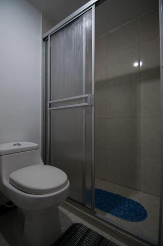 a bathroom with a toilet and a glass shower at 3'min del Parque del Café Apto y Piscina in Montenegro