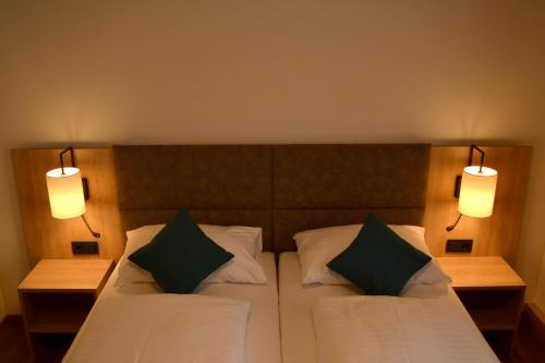 a bedroom with a bed with two pillows and two lights at Gasthof Kranerwirt in Lannach