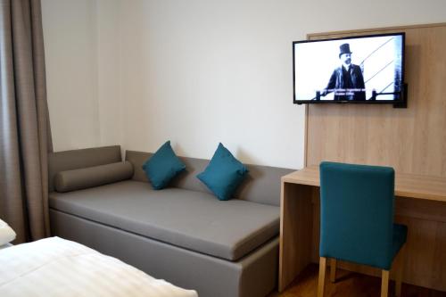 Zimmer mit Sofa und TV an der Wand in der Unterkunft Gasthof Kranerwirt in Lannach