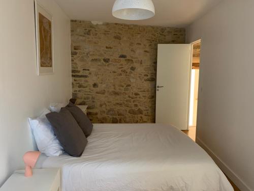 ヴァンヌにあるAppartement d'architecte vue portの白いベッドとレンガの壁が備わるベッドルーム1室が備わります。