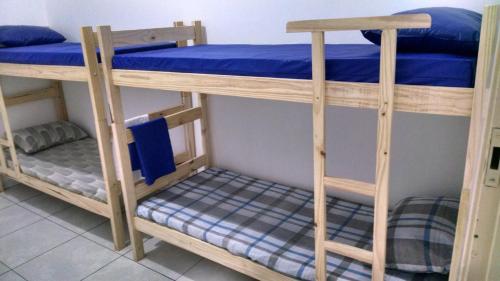 two bunk beds in a room with blue sheets at Pousada Casa 6 in São Vicente