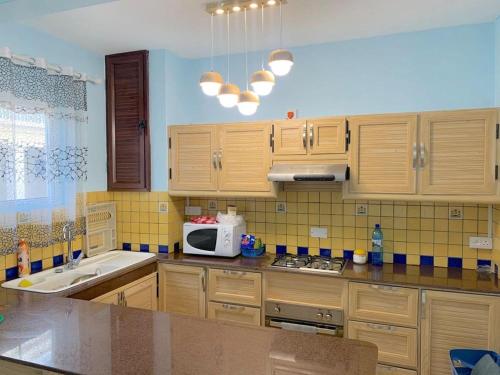 cocina con armarios de madera y microondas blanco en Well equipped peaceful 3 bedroom apartment, en Flic en Flac