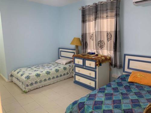 a childs bedroom with two beds and a dresser and curtains at Well equipped peaceful 3 bedroom apartment in Flic-en-Flac