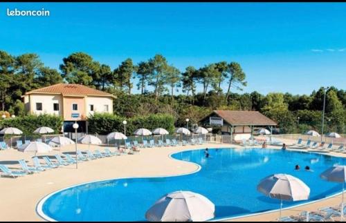 une grande piscine avec chaises et parasols dans l'établissement Soustons plage Maison terrasse 2 pers et 1 enfant Les villas du lac Tennis mini golf, à Soustons