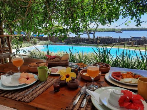 a wooden table with food and drinks and a pool at Casa Valentine Pousada Itacaré in Itacaré