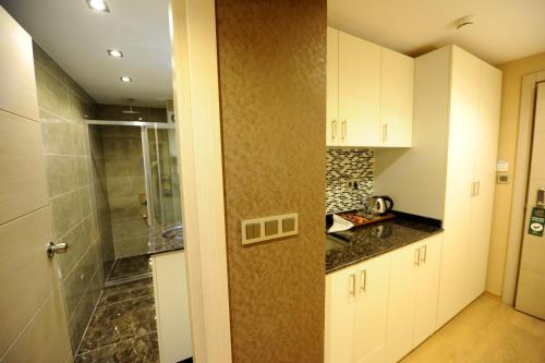 a kitchen with white cabinets and a walk in shower at Rooms Inn Taxim in Istanbul