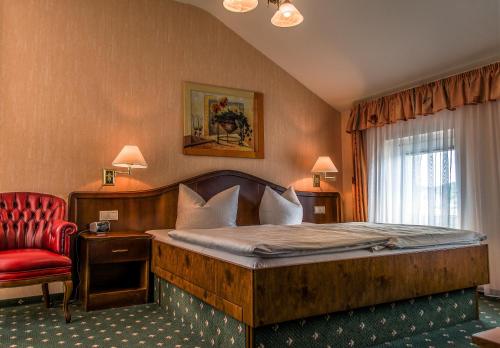 a bedroom with a large bed and a red chair at Hotel Meereswelle - Anno 1875 in Ahlbeck