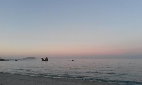 a beach with rocks in the water at sunset at Agriturismo Su Barraccu in Loceri