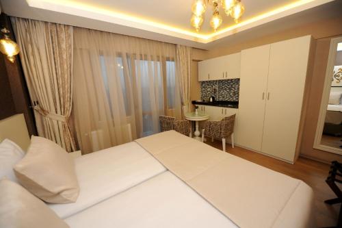 a bedroom with a white bed and a kitchen at Rooms Inn Taxim in Istanbul