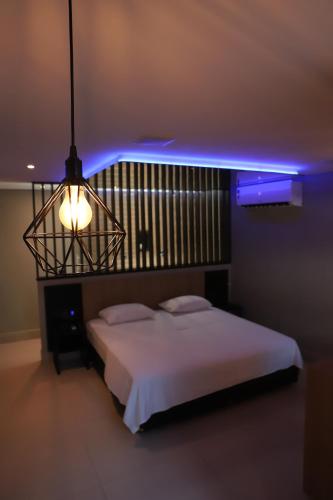 a bedroom with a white bed and a blue light at Drops Motel Barretos in Barretos