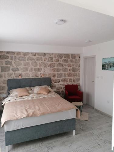 een slaapkamer met een bed en een bakstenen muur bij VILA MIRA in Trebinje