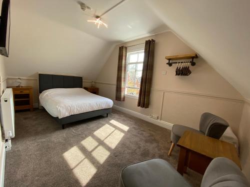 a attic room with a bed and a table and chairs at Fairlawns Guest House in Banbury