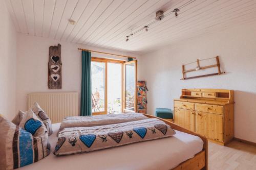 a bedroom with a bed and a dresser and a window at Haus Netzer in Bartholomäberg