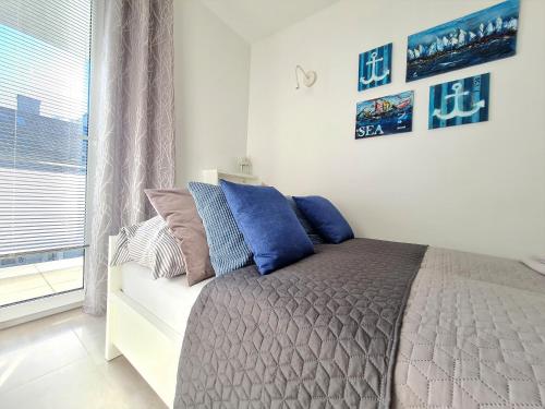 a bedroom with a bed with blue pillows and a window at Apartment 1A in Świnoujście