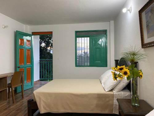 a bedroom with a bed and a vase of flowers on a table at Hotel Campestre Paraiso Cafetero in Montenegro
