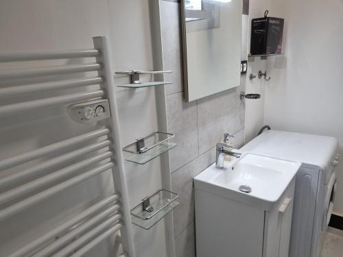 une salle de bain blanche avec un lavabo et un miroir dans l'établissement Appartement T3, cosy, climatisé, équipé avec goût, à Avignon