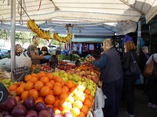 um grupo de pessoas em torno de uma banca de frutas em um mercado em Stesi Vacanze em Roma