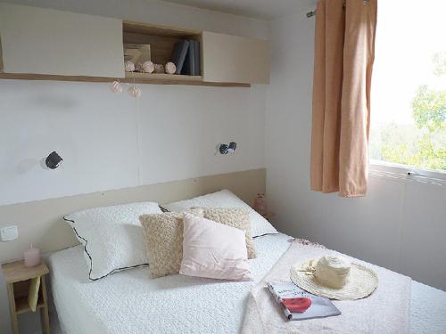 um quarto com uma cama com almofadas e uma janela em Les Dunes de Contis em Saint-Julien-en-Born