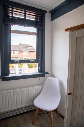 a white chair in a room with a window at Bed and Wine Nonsolovino in Reeuwijk