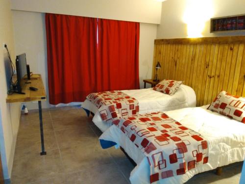 1 dormitorio con 2 camas y cortina roja en Hostal El Korú en San Carlos de Bariloche