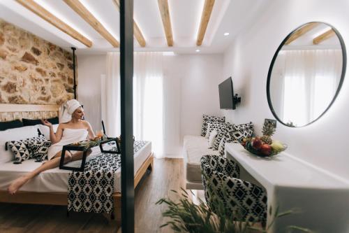 een vrouw op een bed in een kamer met een spiegel bij Rodillo Apartments in Plaka