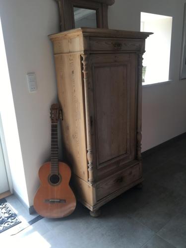 a guitar sitting next to a wooden cabinet at Vita og Pouls Gård - Guesthouse in Viby