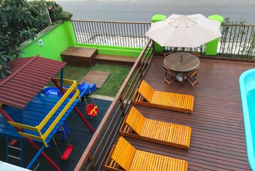 a deck with chairs and a table and an umbrella at POUSADA NOSSO LAR in Guarujá