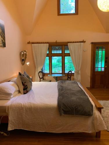 a bedroom with a large white bed with windows at Quail Farm, Colonial charm in Nelson