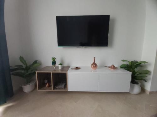 a white cabinet with a flat screen tv on a wall at Ideal Appart Ain Zaghouan Tunis in El Aouina