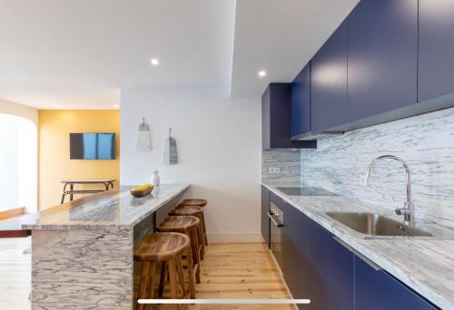 eine Küche mit blauen Schränken, einer Spüle und Stühlen in der Unterkunft Lemon Tree Family Apartment in Porto