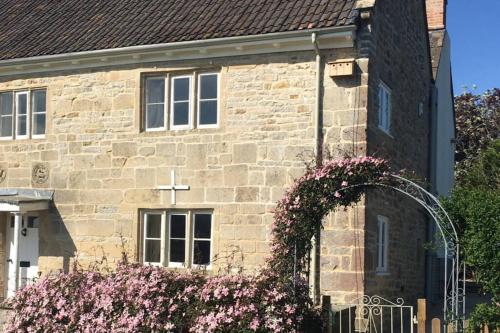 a stone church with a cross on the side of it at 16 Century Farmhouse Cottage, foothills of iconic Glastonbury Tor. in Glastonbury