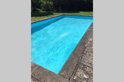 a swimming pool with blue water in a yard at 16 Century Farmhouse Cottage, foothills of iconic Glastonbury Tor. in Glastonbury