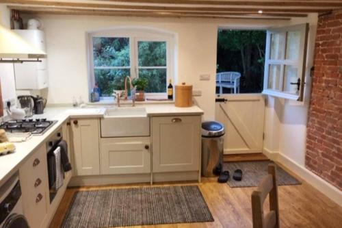 a kitchen with a sink and a stove and windows at 16 Century Farmhouse Cottage, foothills of iconic Glastonbury Tor. in Glastonbury