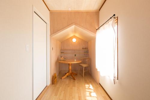 ein kleines Esszimmer mit einem Tisch und einem Fenster in der Unterkunft tathata in Karuizawa