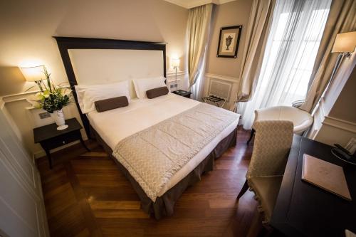 a bedroom with a large bed and a chair at Victoria Hotel Letterario in Trieste
