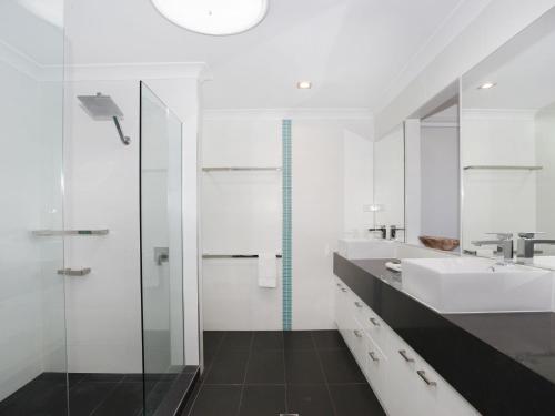 a white bathroom with a sink and a shower at 4 bedroom home on canal in Mooloolaba