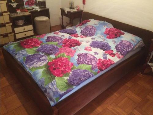 a bed with a blanket with flowers on it at Room in apartment with a host in the center of Bar in Bar