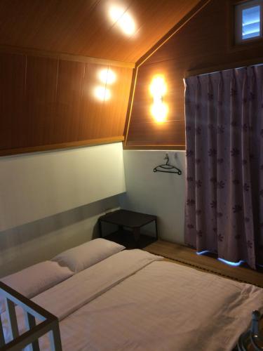 a small bedroom with two beds and a window at Oliver Tree B&B in Fenglin