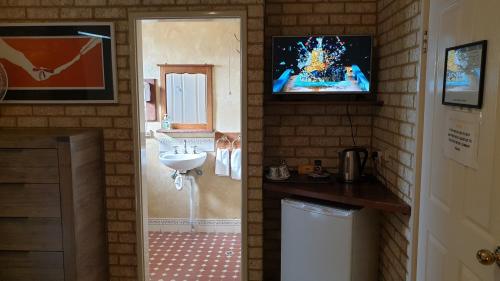 a bathroom with a television and a painting on the wall at Baywatch Manor Augusta in Augusta