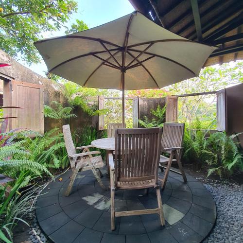 a table with two chairs and an umbrella on a patio at Yabbiekayu in Yogyakarta