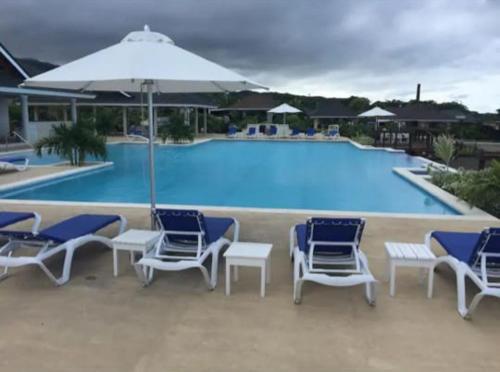 a swimming pool with blue and white chairs and an umbrella at A home away from home in Richmond