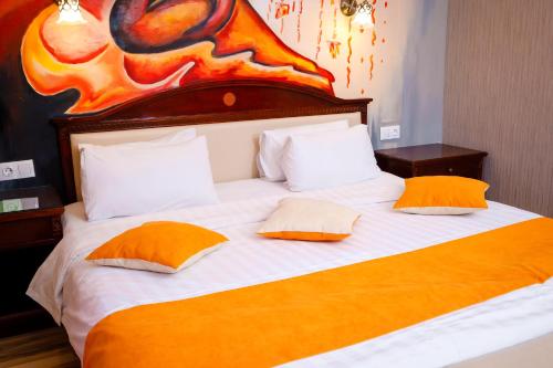 a large bed with two orange pillows on it at G Empire in Astana