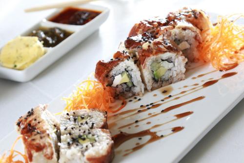 a white plate with sushi and a bowl of sauce at Crowne Plaza Leon by IHG in León