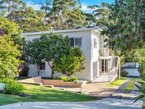 una casa blanca con árboles delante en Akora House at Hyams Beach, en Hyams Beach