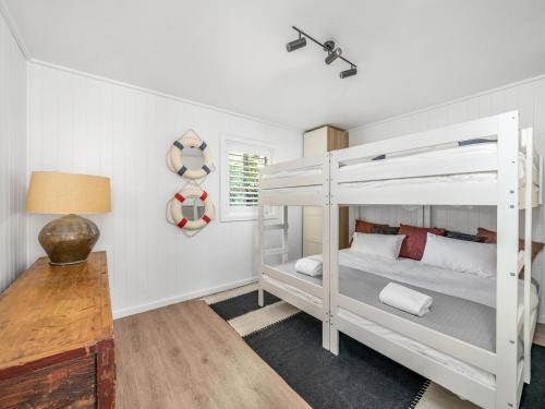 Un dormitorio con dos literas y un escritorio. en Akora House at Hyams Beach, en Hyams Beach