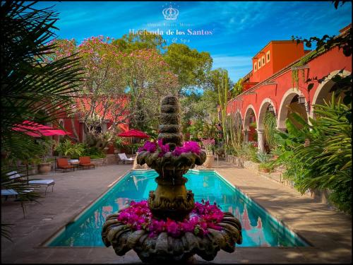 une fontaine avec des fleurs roses à côté d'une piscine dans l'établissement Hacienda de los Santos, à Álamos